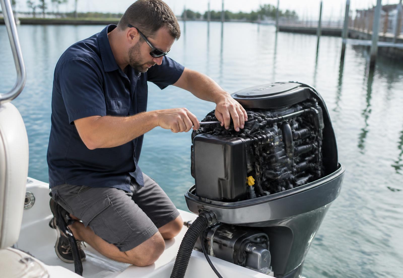 Marine technician servicing an outboard engine at a dock